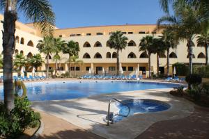 a large swimming pool with palm trees and a building at Apartamento Playa Marina Particular Isla Canela in Huelva