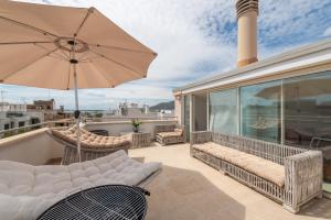 un patio con sillas y una sombrilla en el balcón en Casa REWA, en Puerto de Alcudia