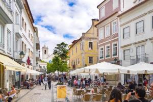 eine Stadtstraße mit Tischen, Stühlen und Gebäuden in der Unterkunft Aveiro Garden's Home in Aveiro