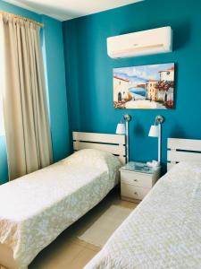 two beds in a bedroom with blue walls at Pool Apartment in Larnaca