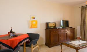 a living room with a table and a tv at Athina Stunning Elounda View Apartment in Elounda