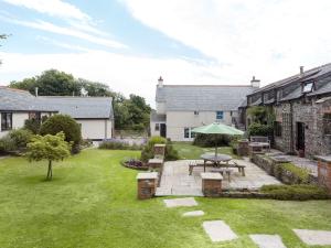 - un jardin avec une table de pique-nique et un parasol dans l'établissement Honey Bee Cottage, à Holsworthy