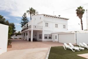 uma casa branca com cadeiras brancas e palmeiras em Villa Conchin Casa junto a Parque Natural em Alberique