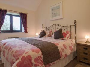 a bedroom with a bed with a floral bedspread at Jenny Wren in Holsworthy