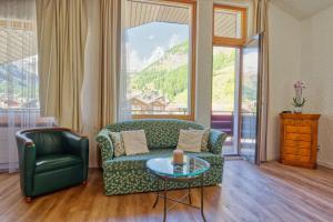 ein Wohnzimmer mit einem grünen Sofa und einem Glastisch in der Unterkunft Hotel Arca Solebad & Spa in Zermatt