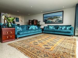 - un salon avec deux canapés bleus et un tapis dans l'établissement Sennen Skies, à Penzance