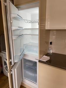an empty refrigerator with its door open in a kitchen at IGNALINOS APARTAMENTAI in Ignalina