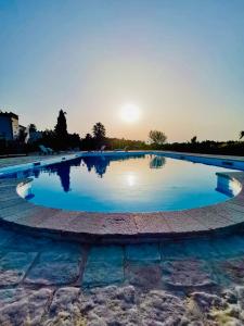 una grande piscina di acqua blu con il sole sullo sfondo di B&B Terre dì Montecoco a San Pancrazio Salentino