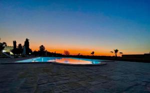 a swimming pool with a sunset in the background at B&B Terre dì Montecoco in San Pancrazio Salentino