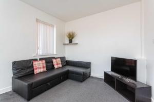 sala de estar con sofá de cuero negro y TV de pantalla plana en Cherry Property - Mulberry Suite, en Blackpool