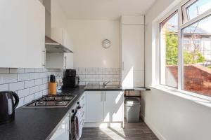 uma cozinha branca com um fogão e uma janela em Cherry Property - Mulberry Suite em Blackpool
