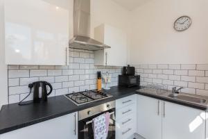 cocina con armarios blancos y fogones en Cherry Property - Mulberry Suite, en Blackpool