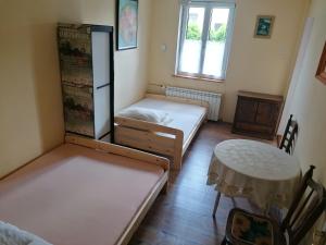 two beds in a room with a table and a refrigerator at Łemkowo Pokoje Gościnne in Lutowiska