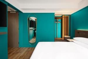 a bedroom with blue walls and a bed with a mirror at Hyatt Centric Midtown 5th Avenue New York in New York