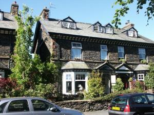 a large stone house with cars parked in front of it at Haisthorpe Guest House in Windermere