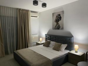 een slaapkamer met een bed met twee nachtkastjes en twee lampen bij De Silva Studio Adia 4 in Mamaia