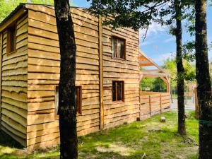 une maison en bois au milieu de quelques arbres dans l'établissement Les Cabanes de Lou-loup écologiques et autonomes, à Anzème