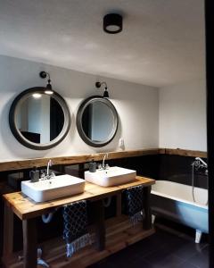 een badkamer met 2 wastafels, een bad en spiegels bij Forest Hill kuća za odmor na Zlataru in Nova Varoš