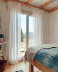 a bedroom with a bed and a large window at Forest Hill kuća za odmor na Zlataru in Nova Varoš