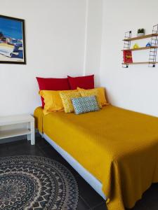 een bed met gele en rode kussens in een kamer bij HORIZON BLEU Vue Mer in Cassis