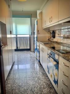 een keuken met een tegelvloer en een groot raam bij MimApartment In Front Beach Oporto in Matosinhos