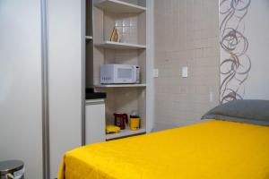 a bedroom with a yellow bed and a microwave at Flat da Vila in Viçosa do Ceará
