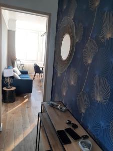 sala de estar con pared azul y espejo en Au gré des marées, appartement face à la mer, classé 3 étoiles en Ault