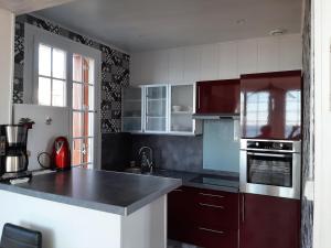 a kitchen with red cabinets and a black counter top at Au gré des marées, appartement face à la mer, classé 3 étoiles in Ault