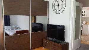 una sala de estar con un centro de entretenimiento con TV y reloj en Apartament Tarnów-Mościce PRZY MOŚCIE en Tarnów