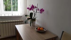 a vase with purple flowers and a bowl of fruit on a table at Apartament Tarnów-Mościce PRZY MOŚCIE in Tarnów