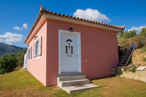 une petite maison rose avec une porte blanche dans l'établissement Efi's Home, à Zakharo