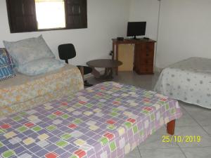 um quarto com uma cama, uma secretária e uma mesa em cantinho do sossego oficial em Caraguatatuba