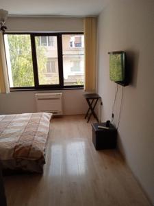 1 dormitorio con cama, ventana y TV en Джессика апартмент, en Veliko Tŭrnovo