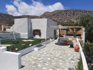 a white building with a patio with a table and an umbrella at Traditional House by The Beach in Agia Theodoti
