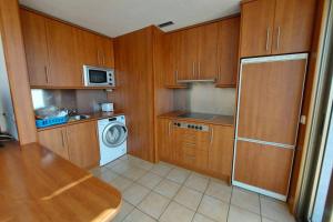 uma cozinha com armários de madeira e uma máquina de lavar roupa em Amplio apartamento en la playa del Esquinzo em Playa Jandia