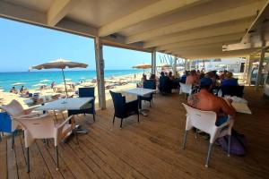 un homme assis sur une terrasse à la plage dans l'établissement Amplio apartamento en la playa del Esquinzo, à Playa Jandía