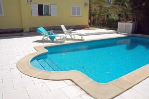 a swimming pool with a chair next to a house at Villa with pool, 200m from beach in Cala Blanca