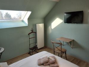 a bedroom with a bed and a table and a television at La Villereautine in Villereau