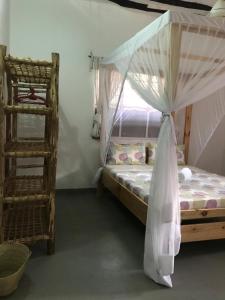 パジェにあるHakuna Matata Guest Houseのベッドルーム1室(天蓋付きベッド1台、はしご付)