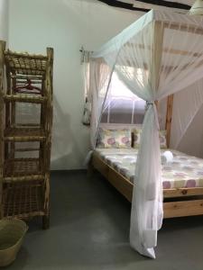 ein Schlafzimmer mit einem Himmelbett und einer Leiter in der Unterkunft Hakuna Matata Guest House in Paje