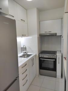 a white kitchen with a sink and a stove at Feels like home 3 in Skopje