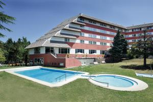 a hotel with a swimming pool in front of a building at Alp Hotel Masella in La Masella