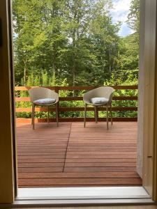 two chairs sitting on a deck with a view of trees at STUDIO BELA in Radovljica