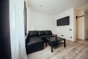 a living room with a black couch and a table at Poorbaltics Apartments in Liepāja