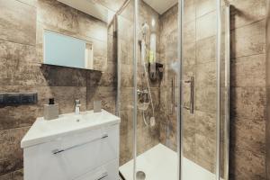 La salle de bains est pourvue d'un lavabo et d'une douche. dans l'établissement Poorbaltics Apartments, à Liepāja