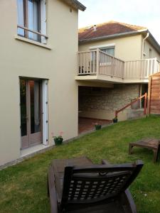 a house with a deck and a table in the yard at Hôtel L'ideal le Mountbatten in Arromanches-les-Bains