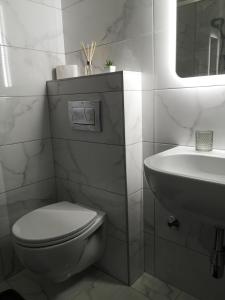 a white bathroom with a toilet and a sink at Apartman Alina Confort in Banja Luka