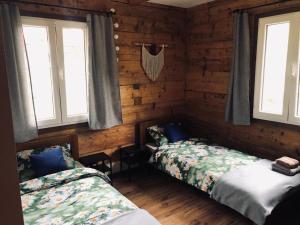 two beds in a room with wooden walls and windows at Dusza Chata w Bieszczadach in Myczkowce