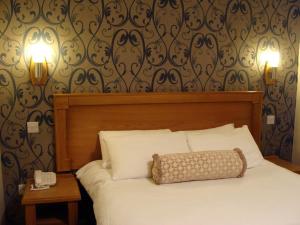 a bed with a white comforter and pillows at Creighton Hotel in Cluain Eois