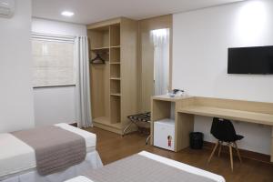a room with two beds and a desk with a television at Roma Hotel in Bacabal